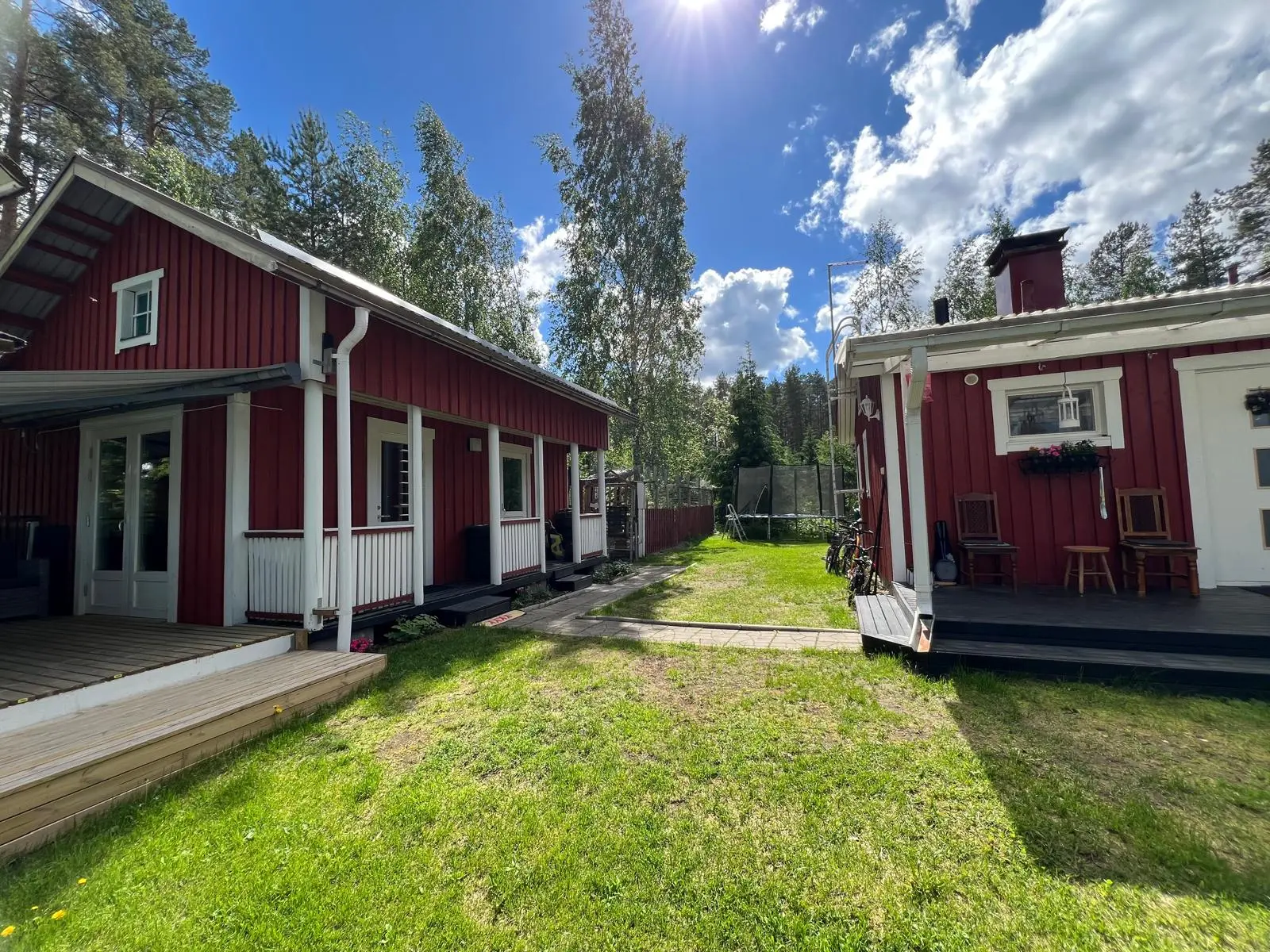 Vehreä piha huvilan ja aitan välissä kesällä