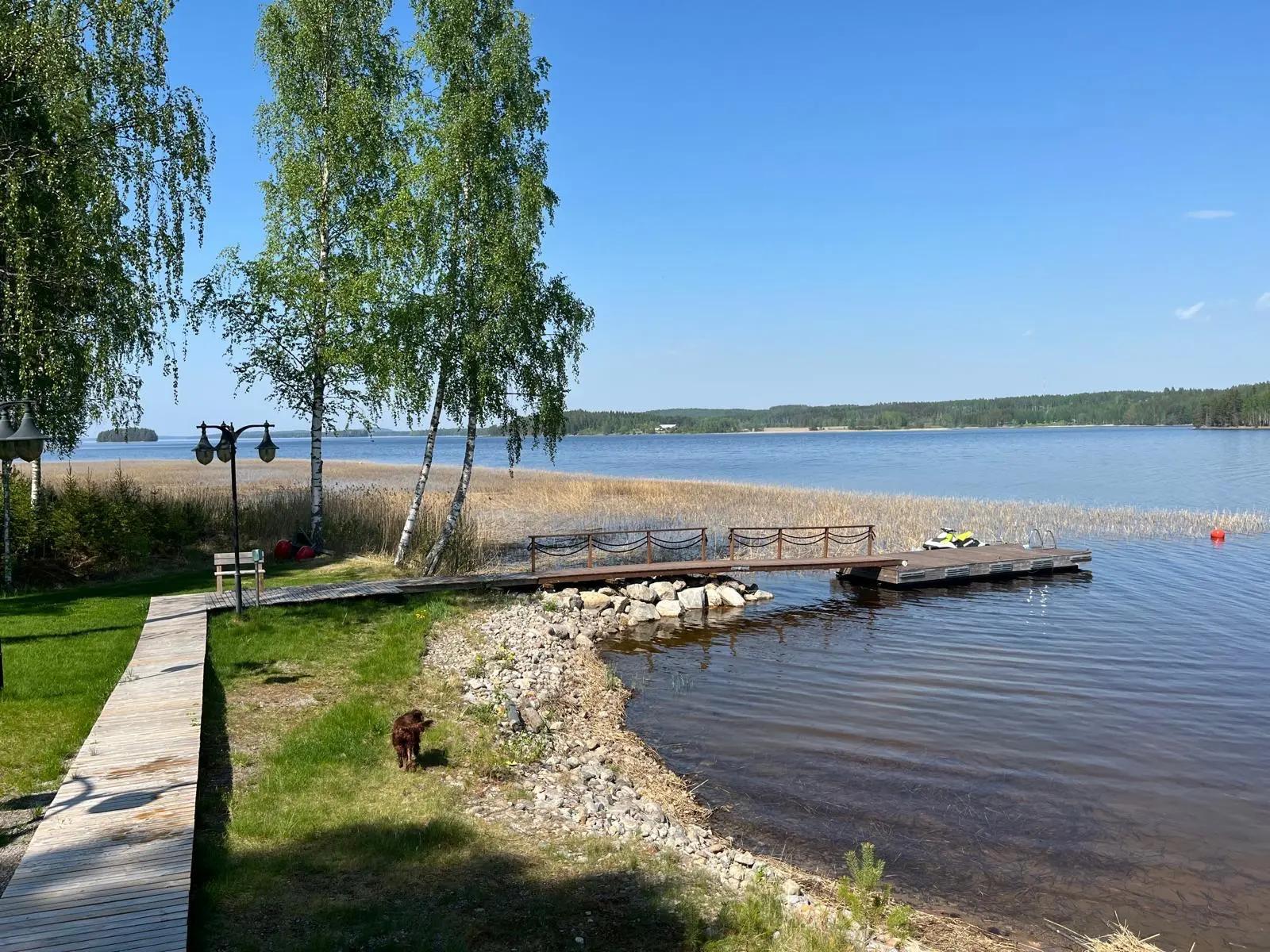 Rantapolku, laituri ja vesijetti järvimaisemassa