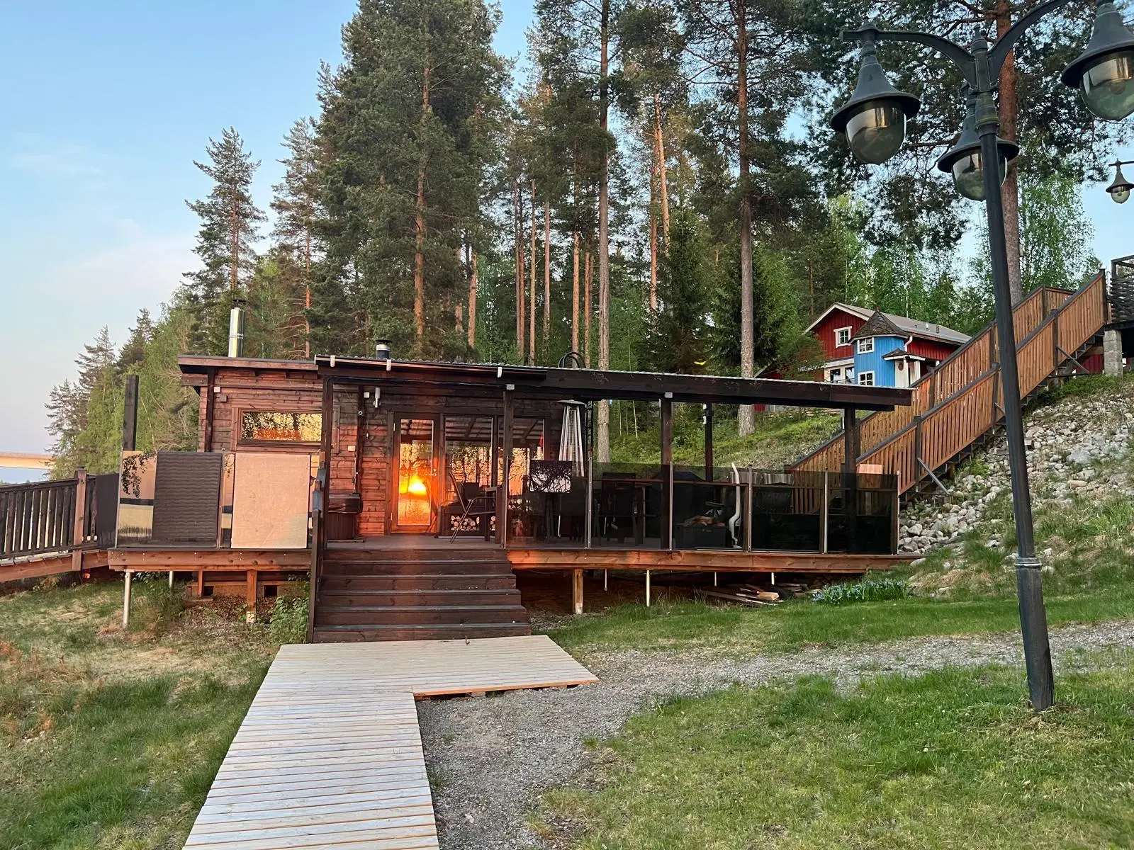 Pitkospuupolku rantasaunan iltavalaistuksessa
