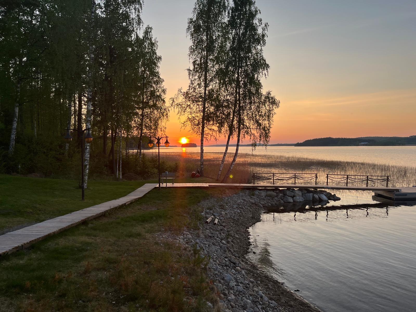 Auringonlasku rantapolulta koivujen ja laiturin ohi